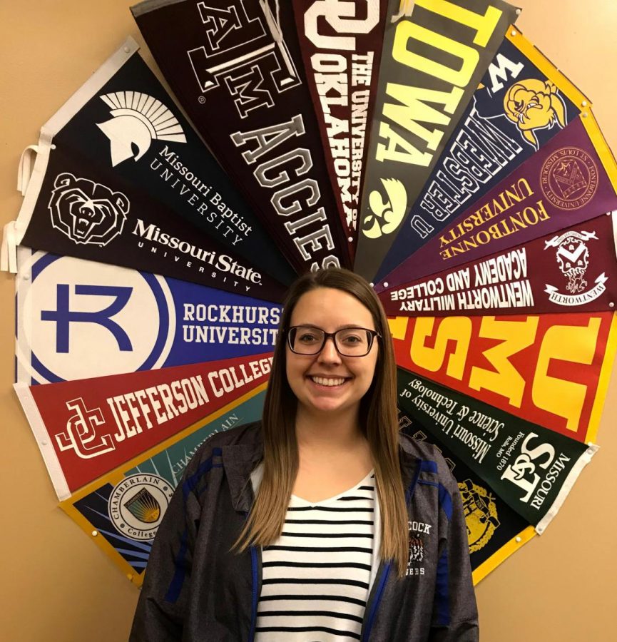 Ms. Lauren Ficker poses in front of her circle of college banners