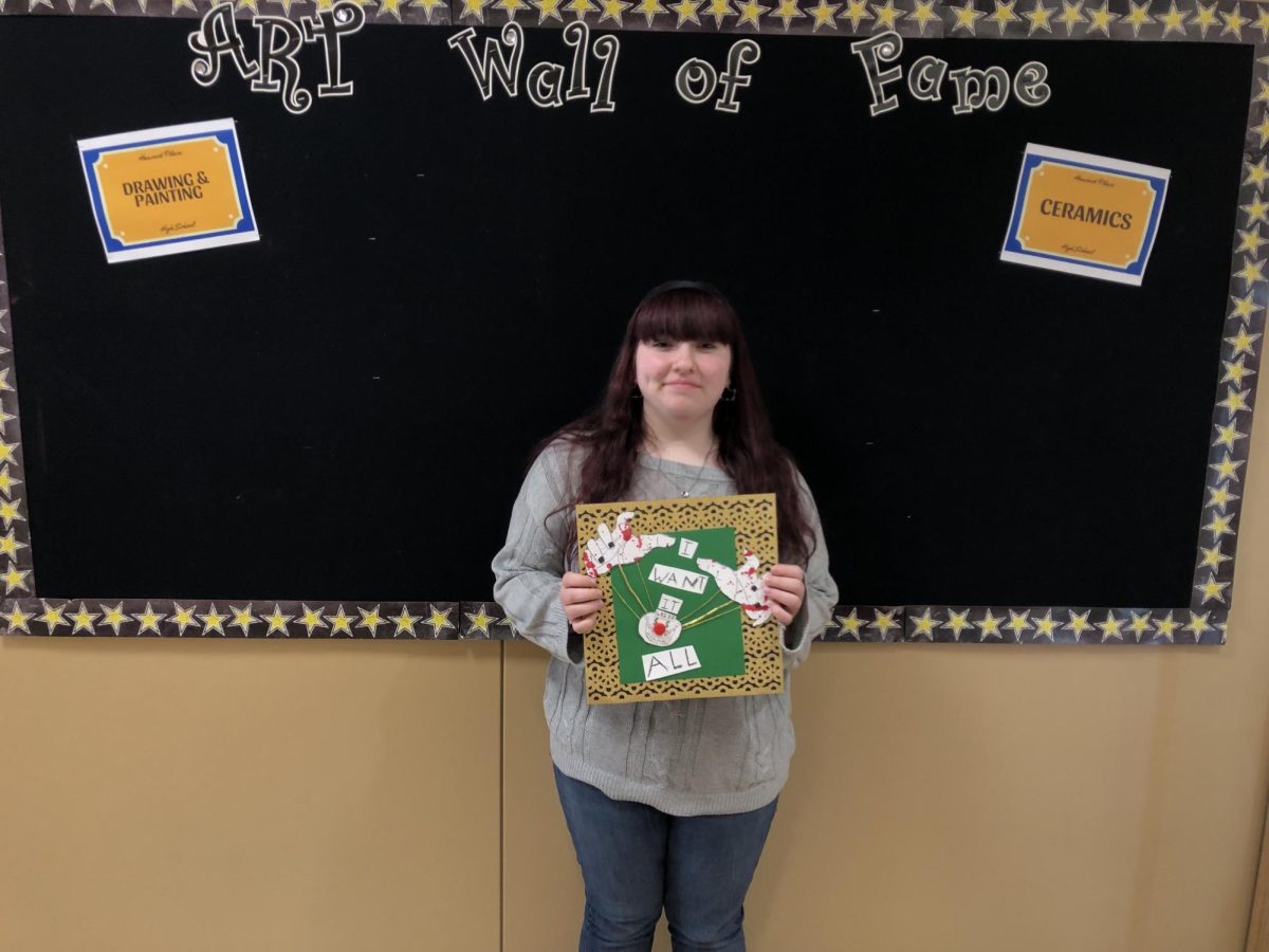 Senior AP Studio Art student Miranda Guss holds "Greed," her favorite of the 15 pieces of her AP Art portfolio submission.