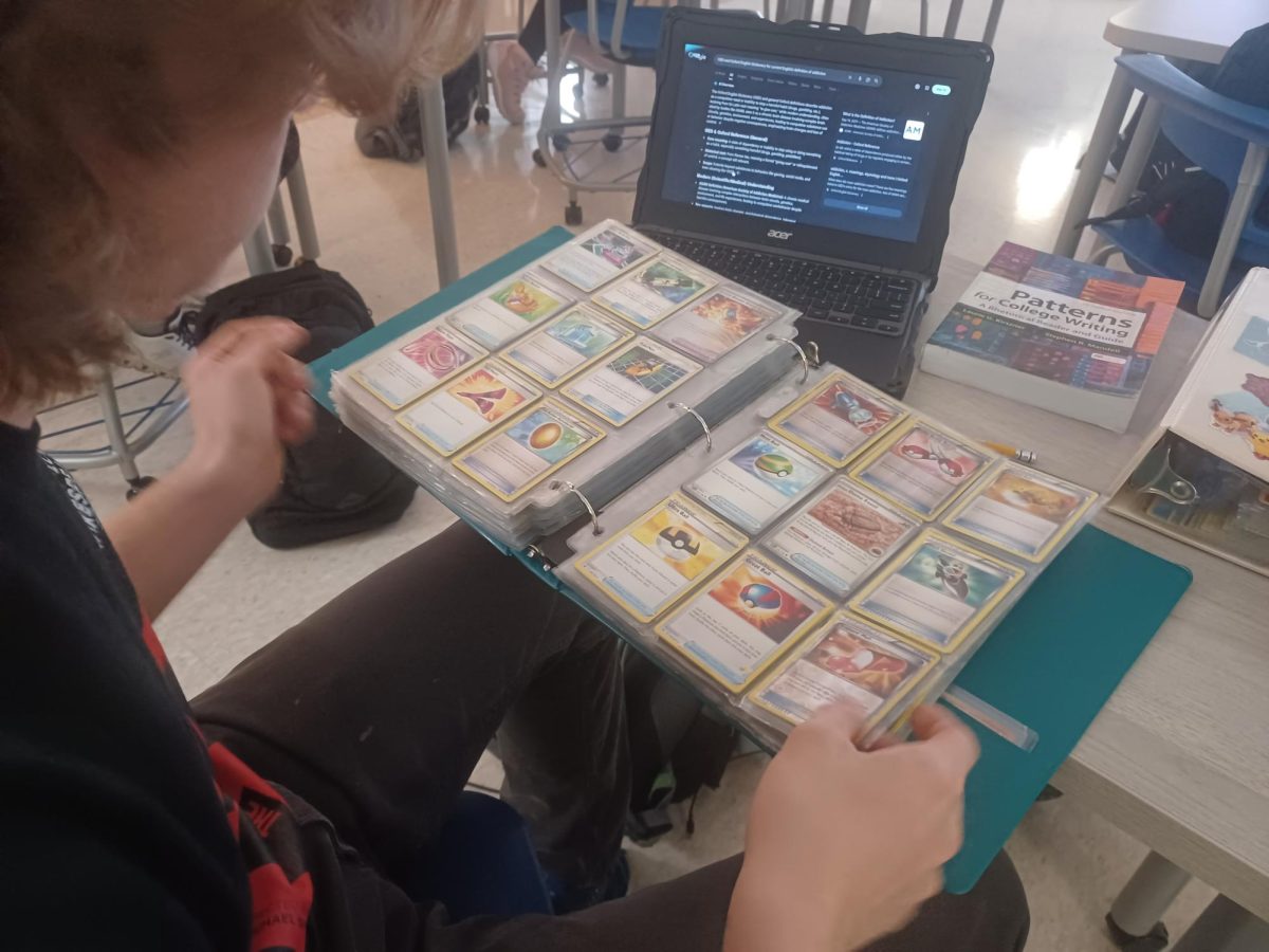 Senior Nick Urbanowicz looks through a binder of Pokémon cards, looking to trade. on Tuesday, December 9th.