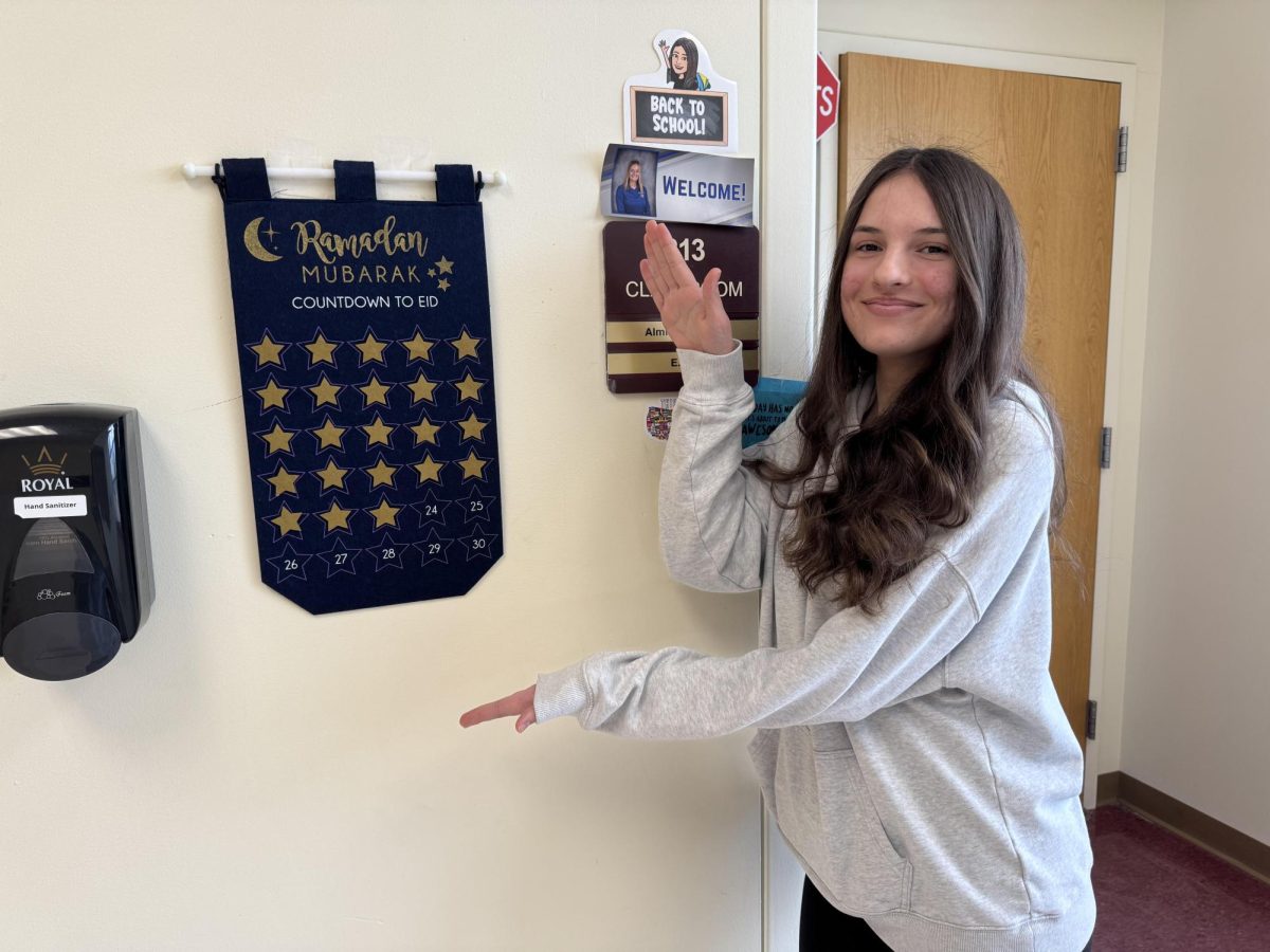 Ariana Durakovic stands next to a "Countdown to Eid" poster presented in the hallway.